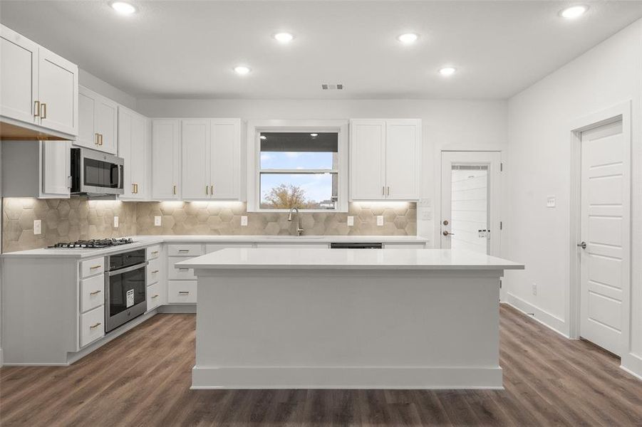 Kitchen with white cabinetry, a tile backsplash and breakfast bar