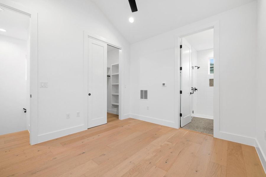 Unfurnished bedroom with light wood-style flooring, vaulted ceiling, recessed lighting, connected bathroom, and ceiling fan Unfurnished bedroom with light wood-style flooring, vaulted ceiling, recessed lighting, connected bathroom, and ceiling fan