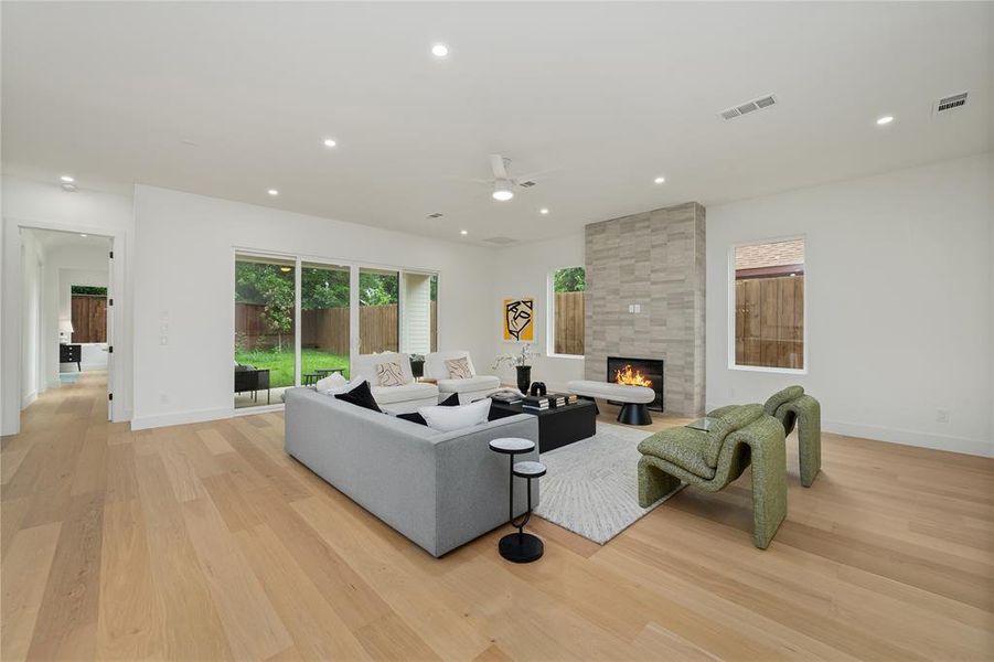 Living room featuring hardwood floors, a gas fireplace with a stone surround, and sliding glass doors that open to the outdoor area