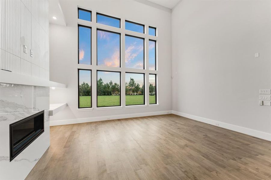 -- Representational Photo -- Two-story Family Room with stunning floor to ceiling stacked windows offering with fireplace creating a great space to gather & entertain in.