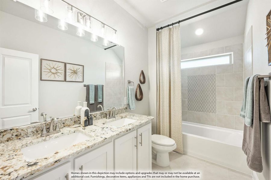 Bathroom with double granite vanity, white cabinets, tub-shower combo with tile surround, and large mirror with overhead lighting.