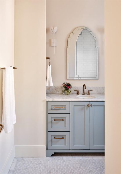 Secondary bath with custom powder blue cabinetry, quartz counters, designer fixtures, designer mirror and floral sconces.
