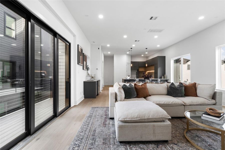 Oversized sliding glass doors extend the living space outdoors, opening to a private balcony tucked within the architectural envelope of the home. Natural light pours in through multiple exposures, reinforcing the home's bright and contemporary aesthetic