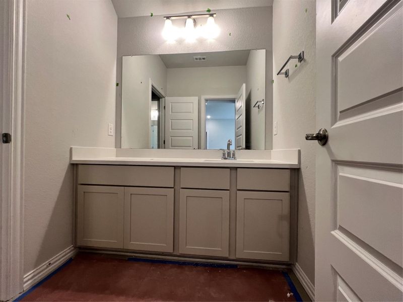 Bathroom with a textured wall and vanity