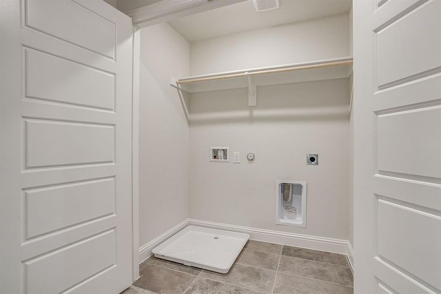 Laundry area featuring gas dryer hookup, electric dryer hookup, washer hookup, and light tile patterned flooring