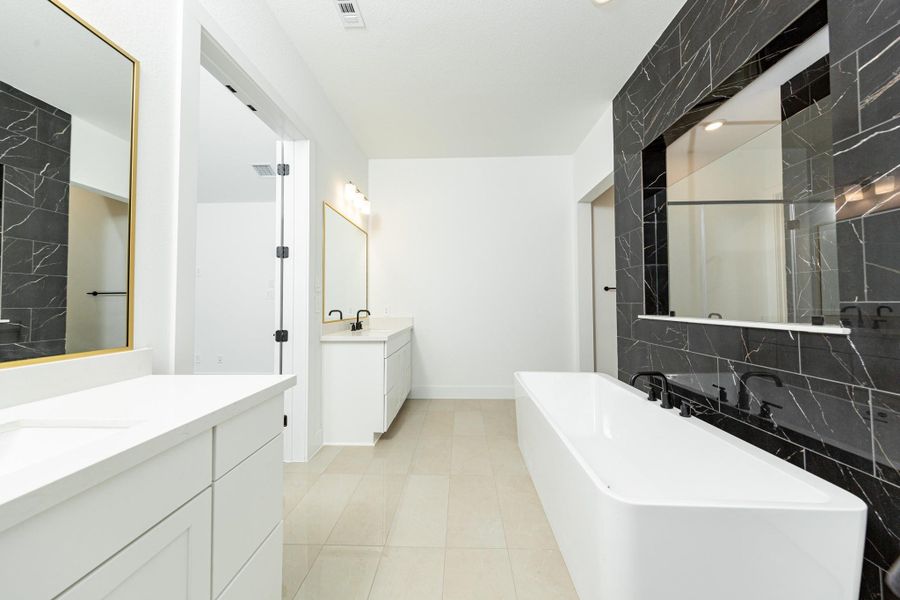 Modern primary bath features dual vanities with sleek white cabinetry, a quartz countertop, framed vanity mirrors, and black matte fixtures for a truly contemporary feel.