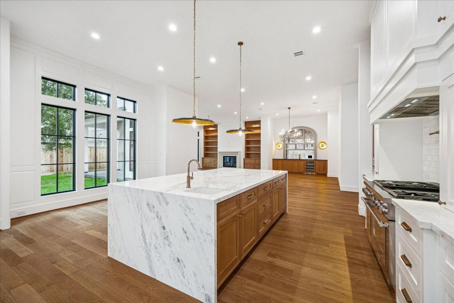 From the island, the sightline extends across the living room toward custom built-ins and continues through to the dining space, underscoring the home’s thoughtful, open-concept design. Warm oak flooring brings cohesion throughout, while subtle wall detailing around the windows elevates the architecture without overwhelming the clean aesthetic. From the island, the sightline extends across the living room toward custom built-ins and continues through to the dining space, underscoring the home’s thoughtful, open-concept design. Warm oak flooring brings cohesion throughout, while subtle wall detailing around the windows elevates the architecture without overwhelming the clean aesthetic.