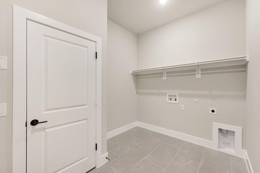 Laundry room with white shelving, washer and dryer hookups, and gray tile floor