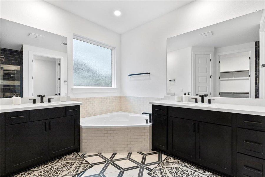 Full bath featuring two vanities, a garden tub, a stall shower, tile patterned floors, and recessed lighting
