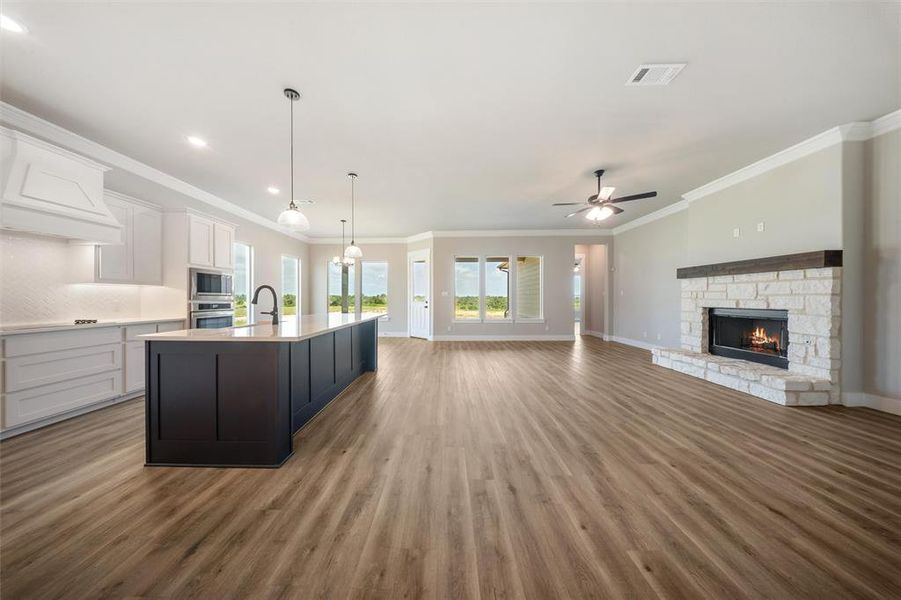 Kitchen with wood finished floors, light countertops, white cabinets, a ceiling fan, and ornamental molding Kitchen with wood finished floors, light countertops, white cabinets, a ceiling fan, and ornamental molding