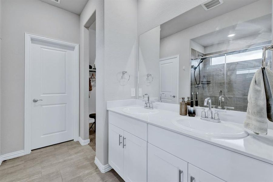 Bathroom featuring a double vanity with two sinks, a large mirror, and a shower with a glass enclosure