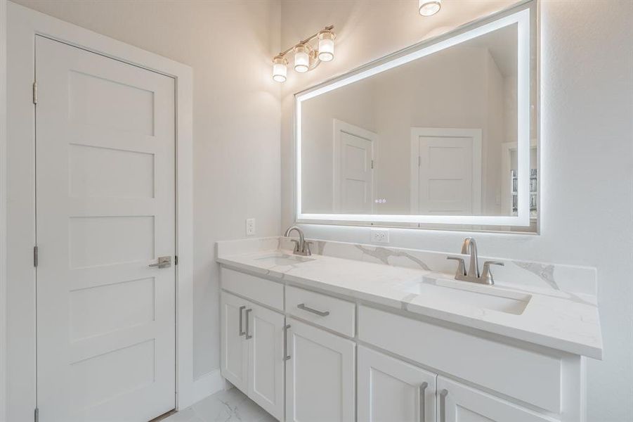Full bathroom with double vanity and baseboards