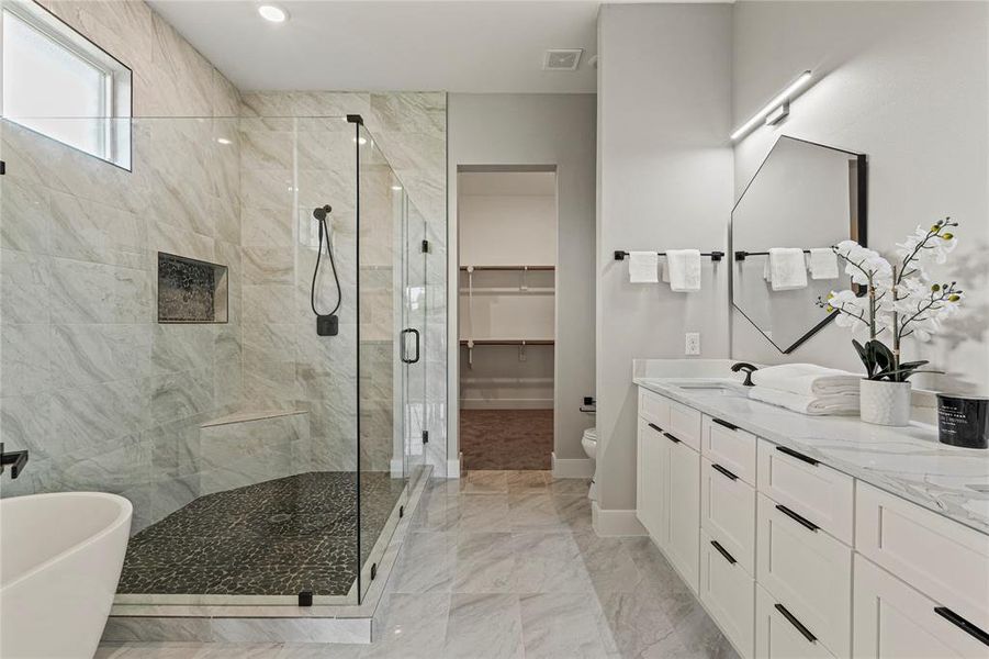 Full bath with a shower stall, a soaking tub, double vanity, marble finish flooring, and a walk in closet