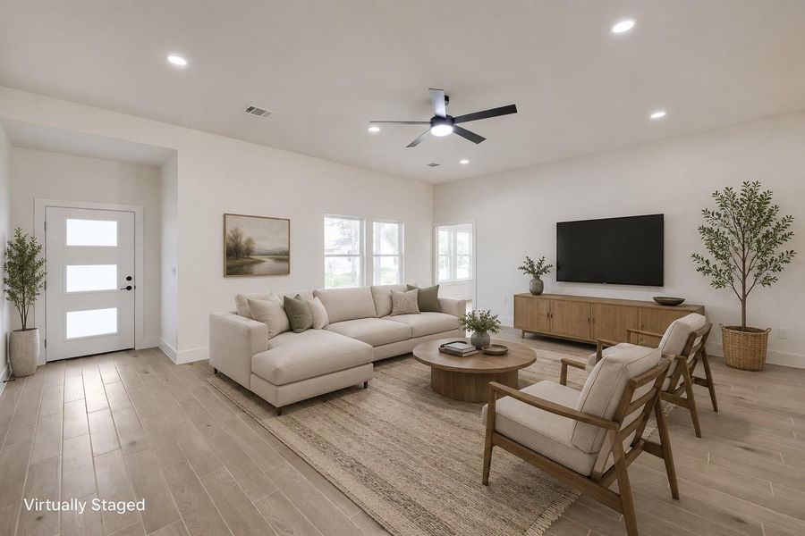 A luminous living space features wide plank flooring and a modern ceiling fan, creating an inviting ambiance.