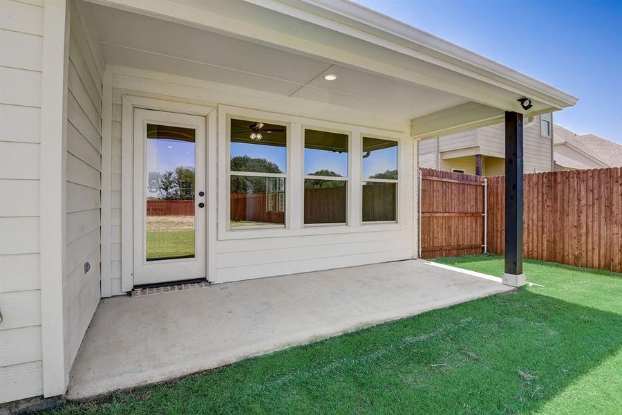 View of exterior entry featuring a lawn and a patio area