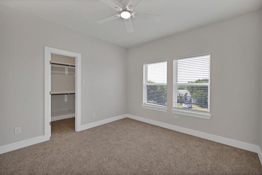 Unfurnished bedroom featuring carpet floors, baseboards, a walk in closet, a closet, and ceiling fan Unfurnished bedroom featuring carpet floors, baseboards, a walk in closet, a closet, and ceiling fan