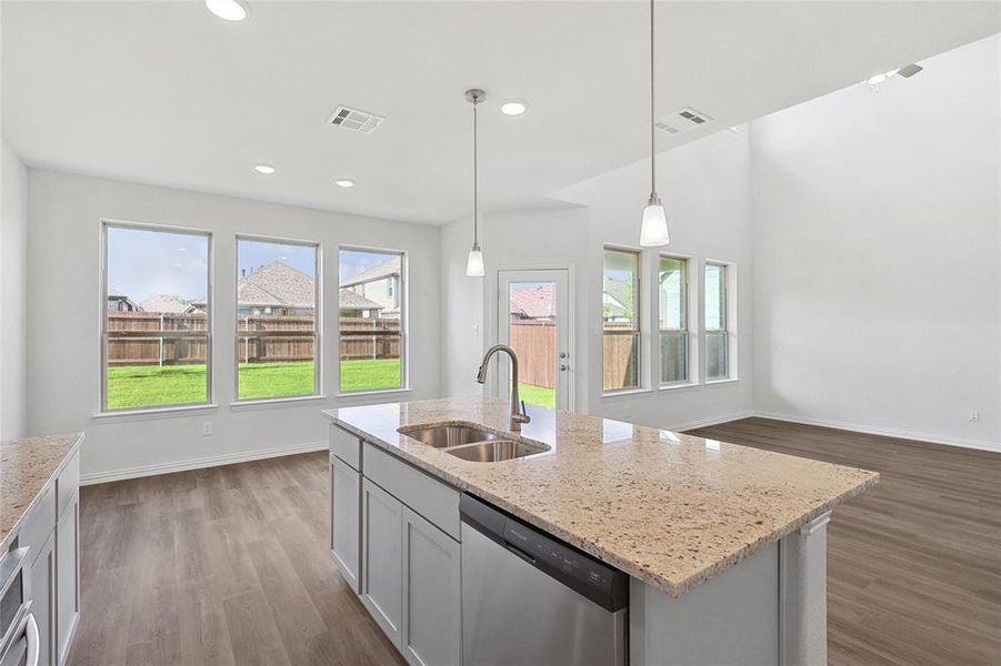 Kitchen with hanging light fixtures, a kitchen island with sink, wood-type flooring, sink, and dishwasher