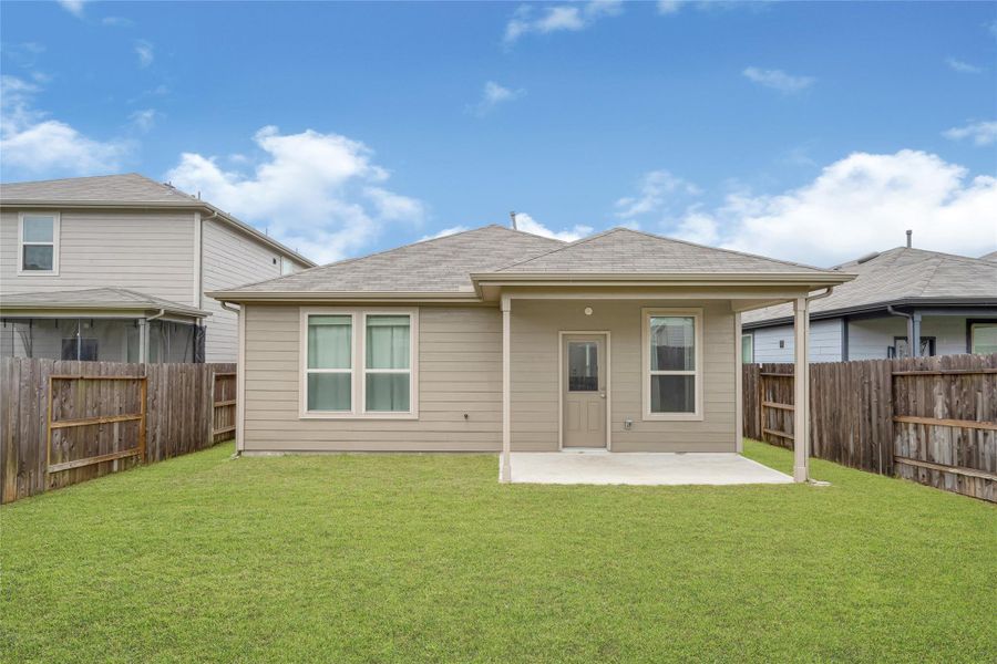 Wide exterior angle of the back of the home, highlighting the neat patio area and tidy siding.
