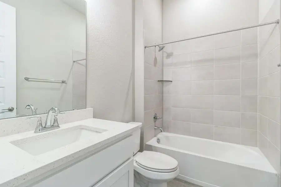 Bathroom featuring vanity, a textured wall, toilet, and shower / washtub combination