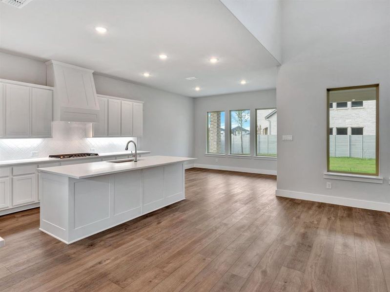 Kitchen featuring light hardwood / wood-style floors, sink, white cabinetry, and an island with sink