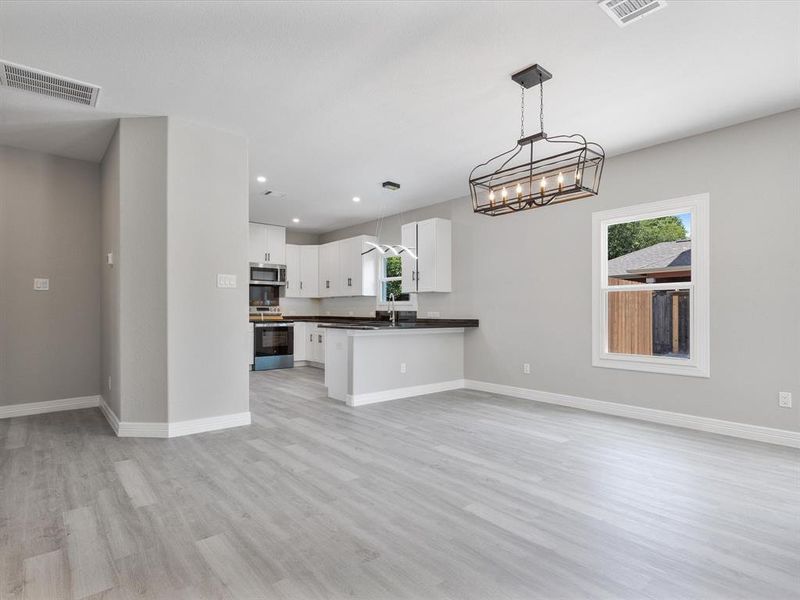 Kitchen featuring appliances with stainless steel finishes, dark countertops, open floor plan, light wood-style floors, and a sink