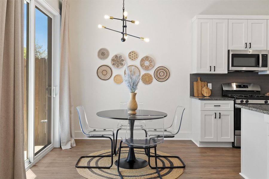 Kitchen with appliances with stainless steel finishes, a chandelier, wood finished floors, and white cabinets Kitchen with appliances with stainless steel finishes, a chandelier, wood finished floors, and white cabinets