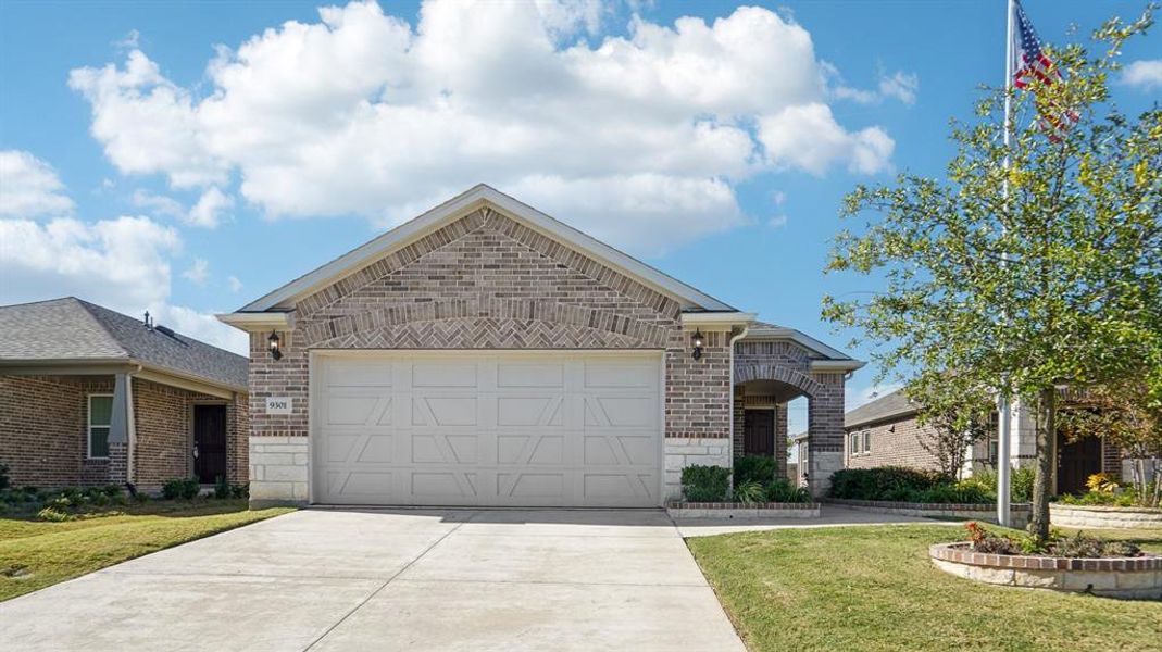 View of front facade featuring brick siding, a front lawn, driveway, and stone siding View of front facade featuring brick siding, a front lawn, driveway, and stone siding