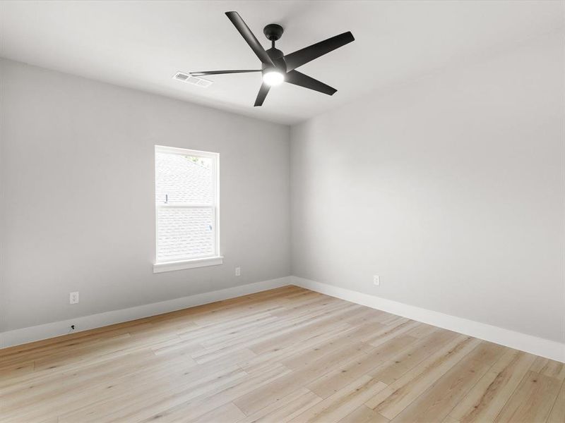 Bright interior room featuring wood-finish flooring, white baseboards, and light gray walls Bright interior room featuring wood-finish flooring, white baseboards, and light gray walls