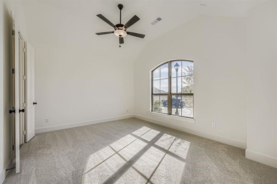 Spare room featuring light colored carpet, ceiling fan, and high vaulted ceiling