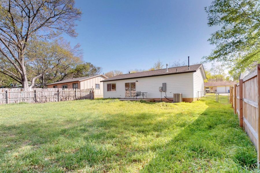 Rear view of property with cooling unit, a yard, and a fenced backyard. Fence on right almost completed. Large yard.