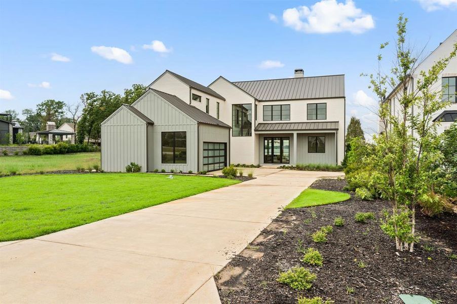 Modern inspired farmhouse with driveway, a front yard, board and batten siding, a chimney, and a standing seam roof Modern inspired farmhouse with driveway, a front yard, board and batten siding, a chimney, and a standing seam roof