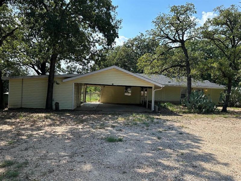 View of side of home featuring driveway and a carport
