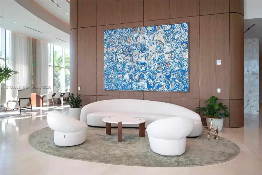 Floor-to-ceiling windows, curved wood-finish wall paneling, and polished stone tile flooring