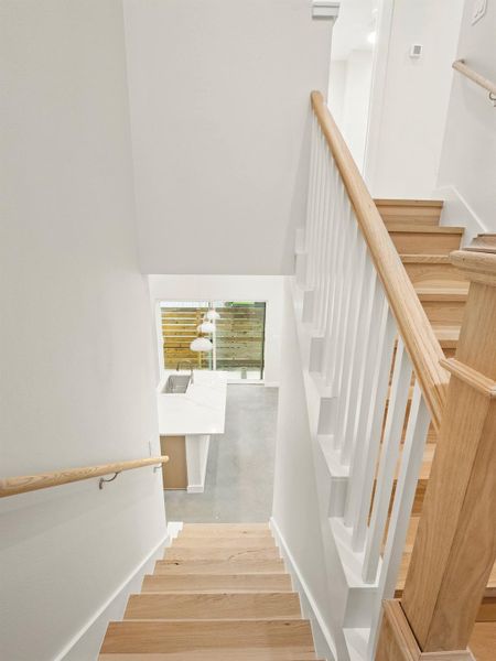 Modern staircase featuring light wood-finish treads and railings