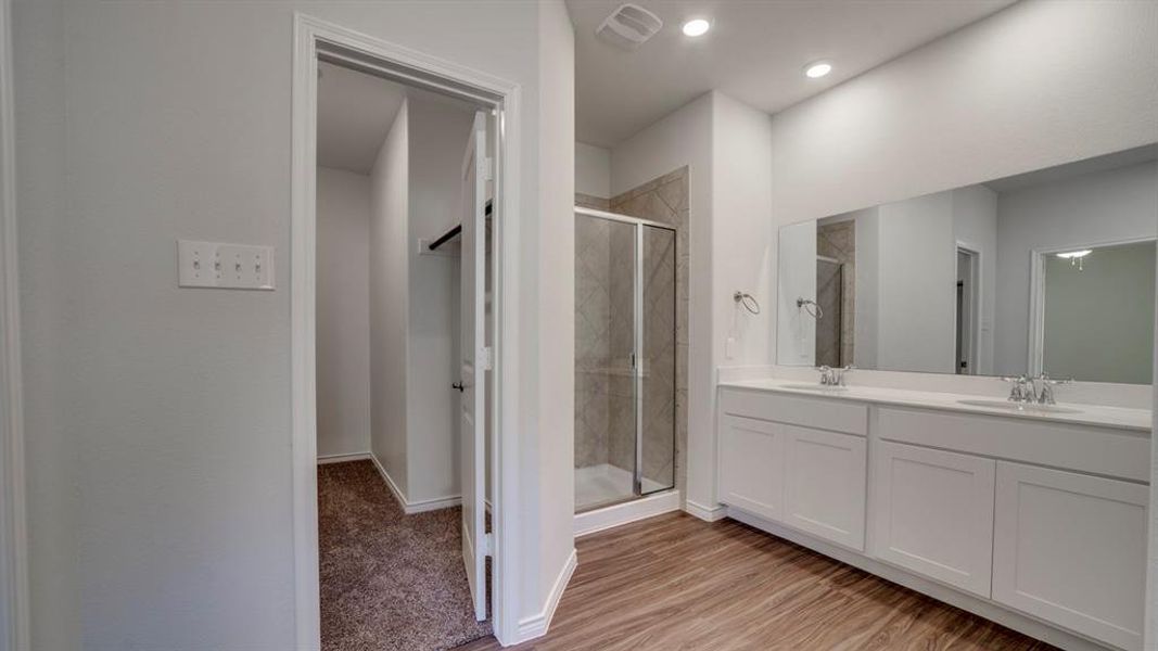 Full bathroom featuring a stall shower, double vanity, light wood-type flooring, and recessed lighting