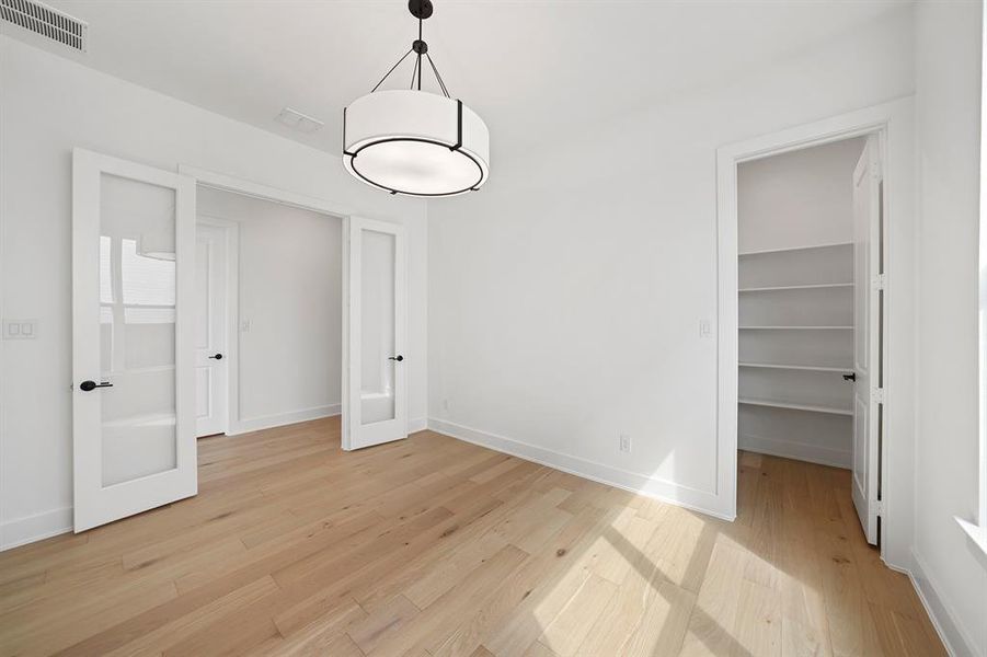 Unfurnished dining area featuring light wood-style flooring and french doors Unfurnished dining area featuring light wood-style flooring and french doors