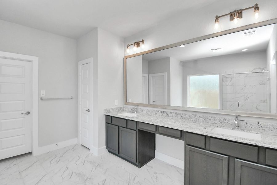 Escape to a spa-like oasis in this primary bathroom. Enjoy a walk-in shower with tile surround, a separate garden tub with custom detailing, and an elegant vanity featuring light countertops, modern hardware, and beautiful recessed lights. Experience luxury and relaxation in every detail. Sample photo of completed home with similar floor plan. Actual colors and selections may vary.