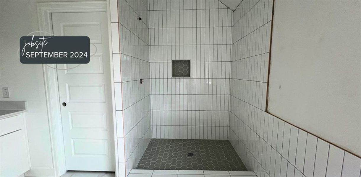 Primary Bathroom Oasis: Step into sophistication with our primary bathroom, featuring tall subway tiles in a stack pattern with contrasting grout and a modern grey shower floor that redefines contemporary luxury.