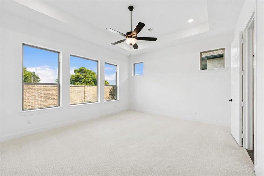 Empty room featuring light colored carpet, a ceiling fan, recessed lighting, and a tray ceiling Empty room featuring light colored carpet, a ceiling fan, recessed lighting, and a tray ceiling