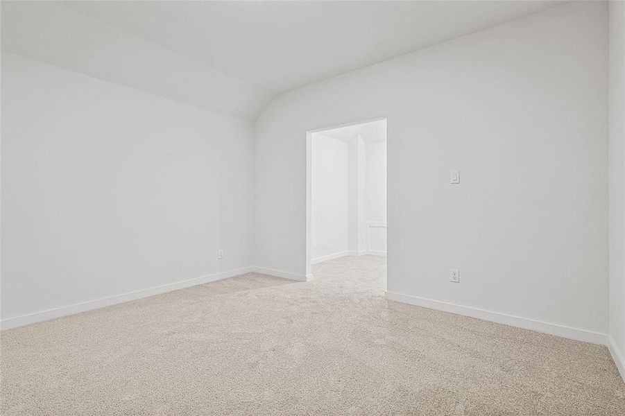 Carpeted empty room featuring vaulted ceiling