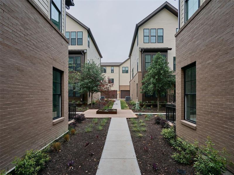 Contemporary townhome exteriors featuring brick and horizontal siding, black-framed windows, and a central courtyard with manicured landscaping