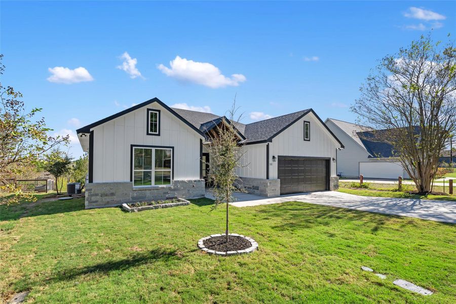 Modern farmhouse style home with board and batten siding, driveway, and stone siding