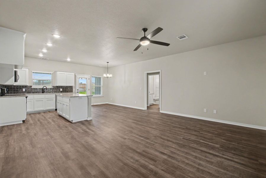 Rich wood-look flooring stretches across a versatile living area connected to the modern kitchen.