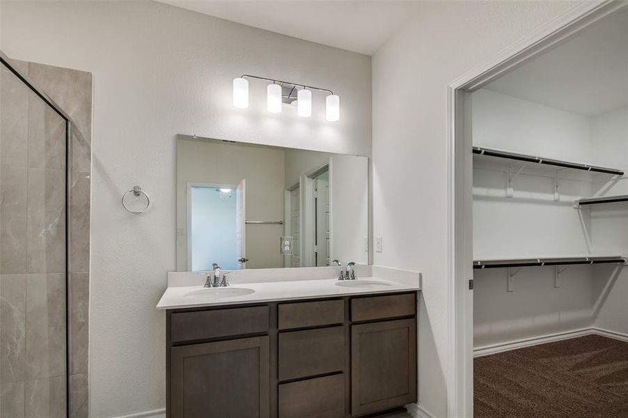 Full bath with double vanity, a tile shower, and a spacious closet Full bath with double vanity, a tile shower, and a spacious closet