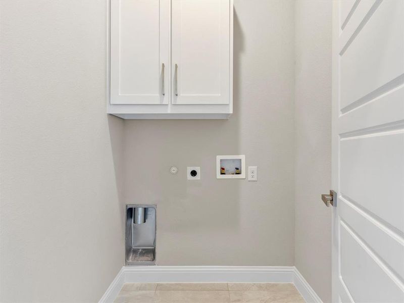 Washroom with washer hookup, light tile patterned floors, hookup for an electric dryer, hookup for a gas dryer, and cabinets