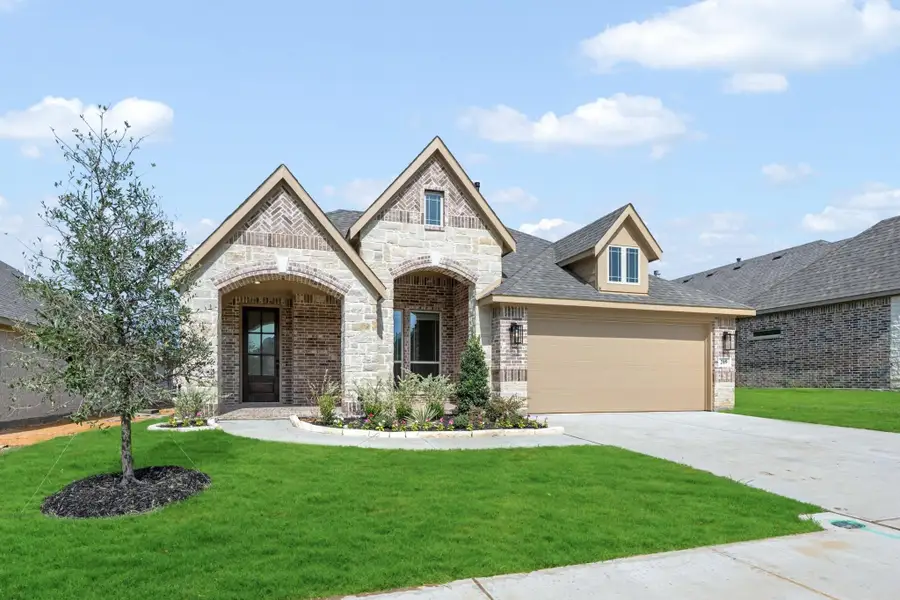 Single-story home with brick and stone exterior, arched entry, two-car garage, and landscaped front yard