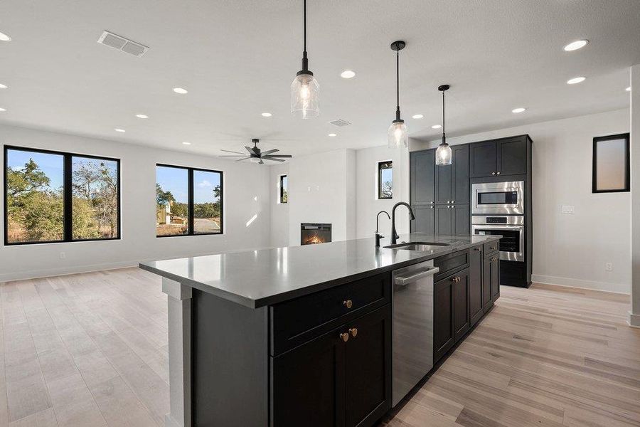 Kitchen with open floor plan, a center island with sink, hanging light fixtures, recessed lighting, and appliances with stainless steel finishes