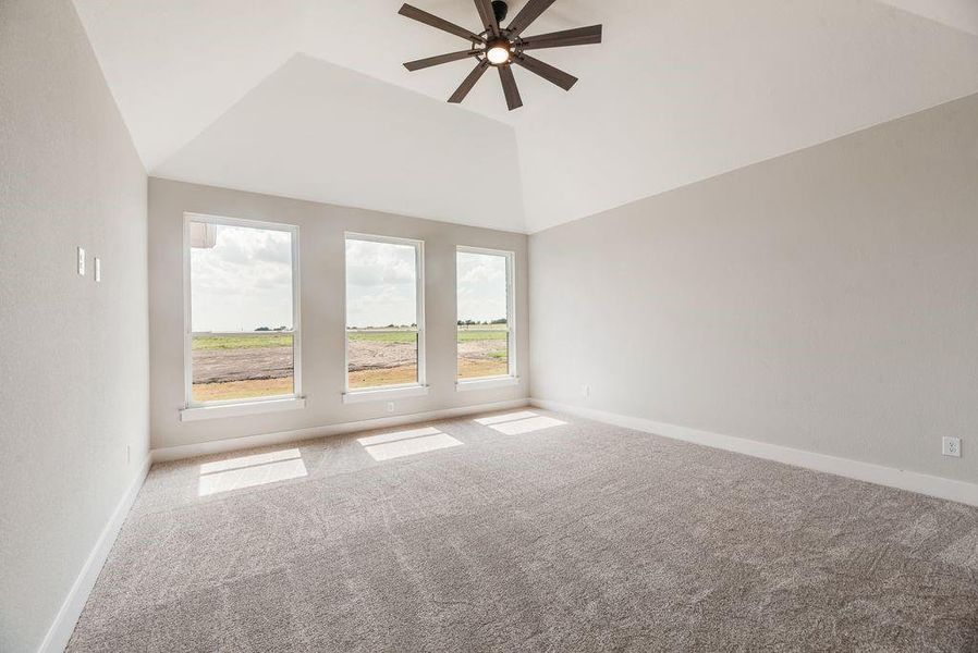 Carpeted empty room featuring plenty of natural light, vaulted ceiling, and ceiling fan Carpeted empty room featuring plenty of natural light, vaulted ceiling, and ceiling fan