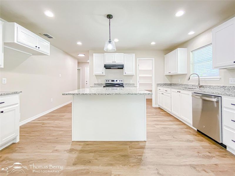 Kitchen with white cabinetry, recessed lighting, light wood-style floors, stainless steel appliances, and light stone countertops Kitchen with white cabinetry, recessed lighting, light wood-style floors, stainless steel appliances, and light stone countertops