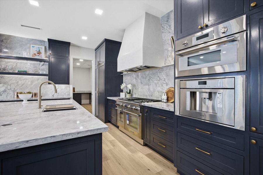 A sculptural vent hood paired with professional-grade cooking surfaces defines a space built for both culinary creativity and visual impact.